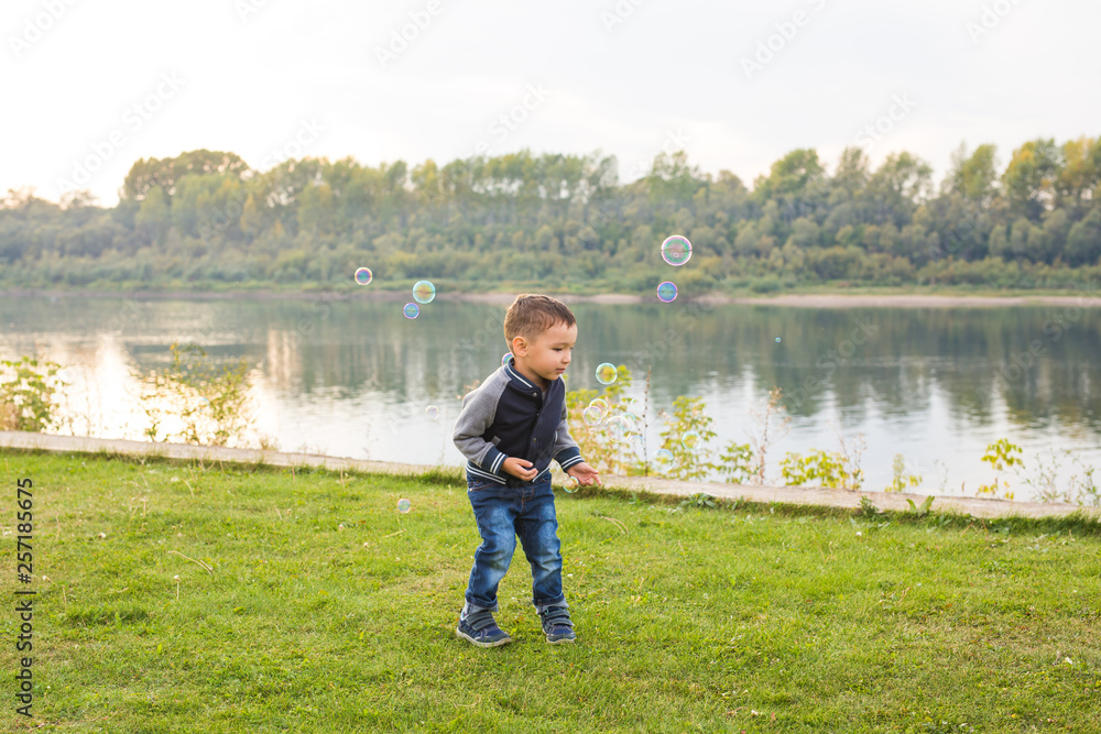 Chilhood, people concept - young boy playing with soap bubbles Chilhood, people concept - young boy playing with soap bubbles