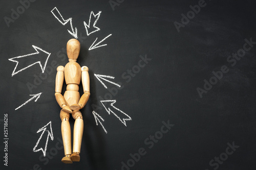 Arrows drawn on a chalk board and a wooden man. The concept of choice.