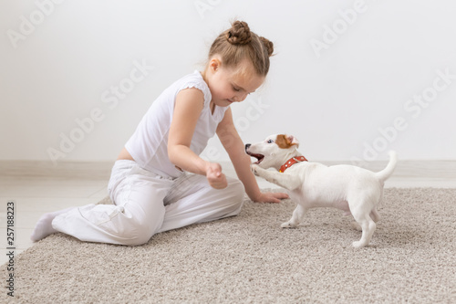 Fototapeta Naklejka Na Ścianę i Meble -  People, pets and animal concept - Little girl sitting on the floor over white background and holding puppy Jack Russell Terrier