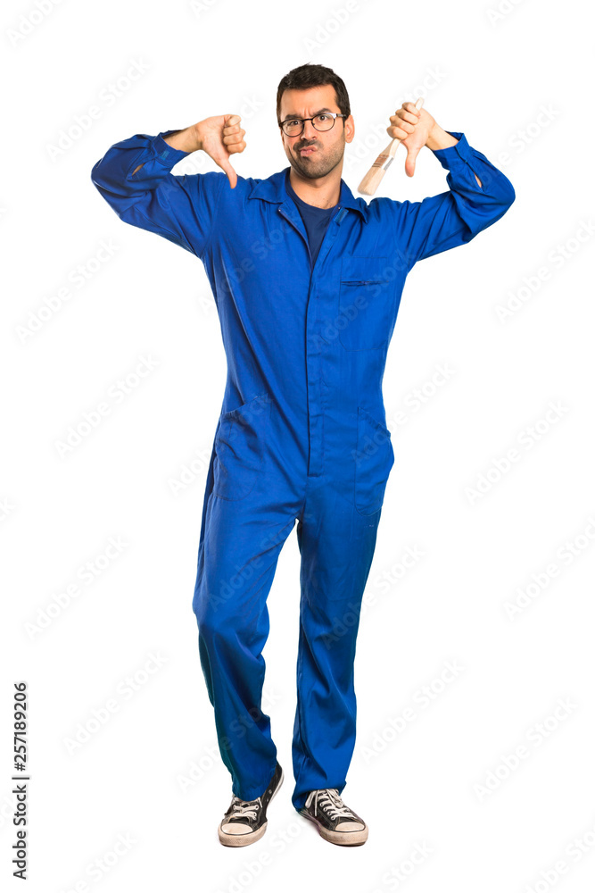 A full-length shot of a Painter man showing thumb down with both hands on isolated white background A full-length shot of a Painter man showing thumb down with both hands on isolated white background
