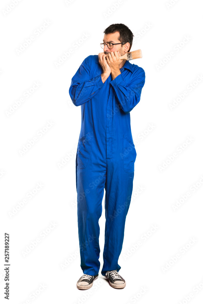 A full-length shot of a Painter man is a little bit nervous and scared putting hands to mouth on isolated white background A full-length shot of a Painter man is a little bit nervous and scared putting hands to mouth on isolated white background