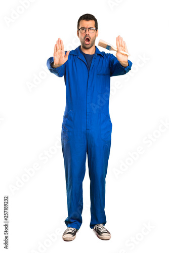 A full-length shot of a Painter man making stop gesture for disappointed with an opinion on isolated white background