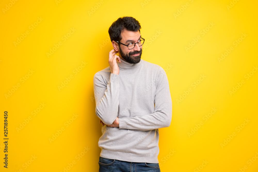 Man with beard and turtleneck thinking an idea while scratching head Man with beard and turtleneck thinking an idea while scratching head