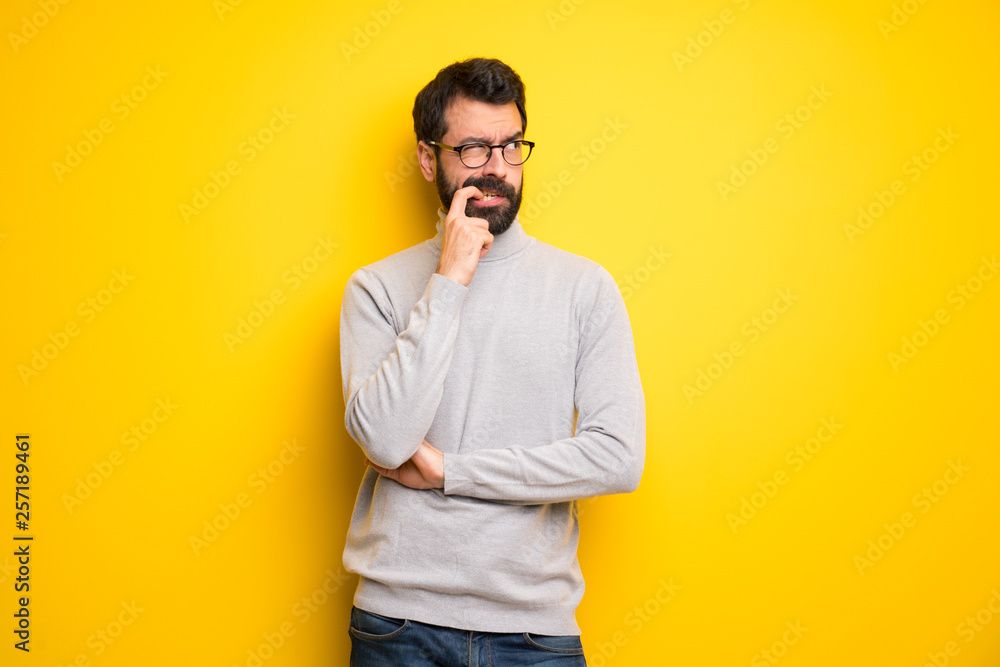 Man with beard and turtleneck having doubts while looking up Man with beard and turtleneck having doubts while looking up