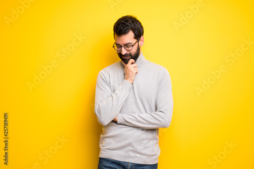 Man with beard and turtleneck looking down with the hand on the chin