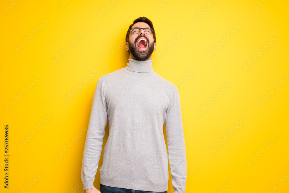 Obraz premium Man with beard and turtleneck shouting to the front with mouth wide open