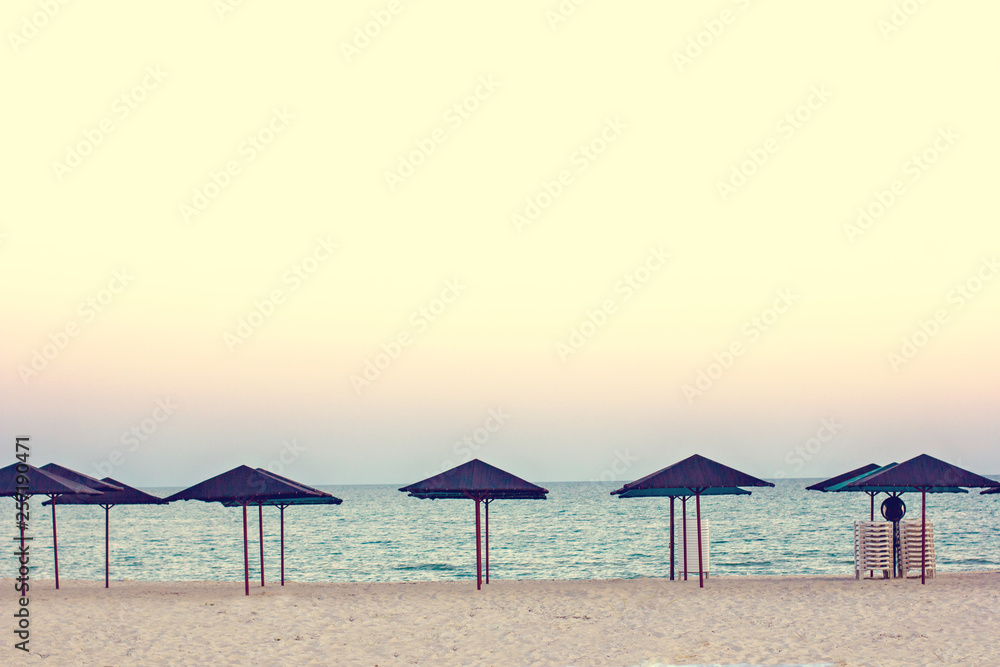 Empty beach, beach umbrellas and beautiful sunset. Romantic atmosphere.