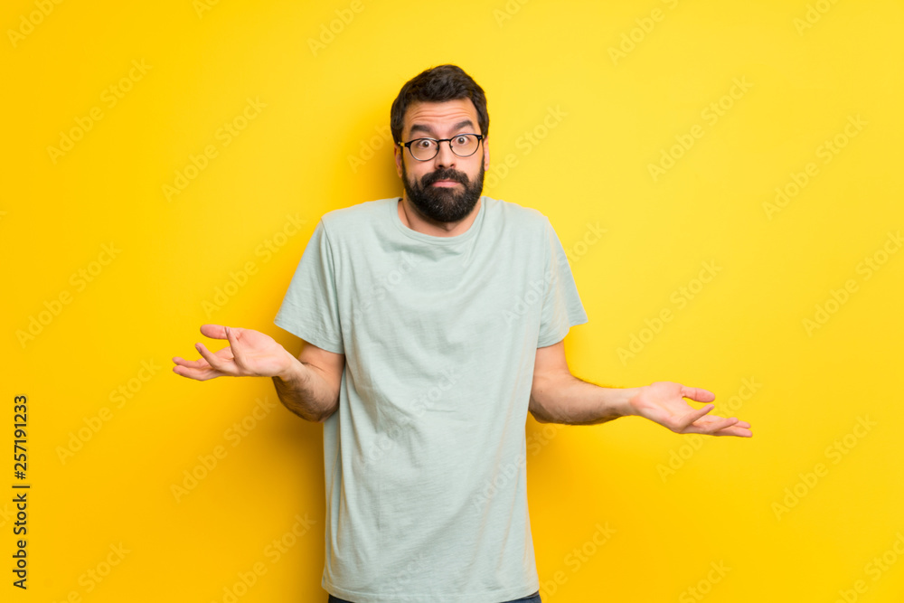 Man with beard and green shirt making unimportant gesture while lifting the shoulders Man with beard and green shirt making unimportant gesture while lifting the shoulders