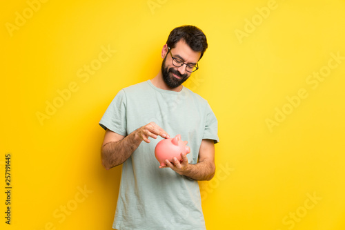 Man with beard and green shirt taking a piggy bank and happy because it is full
