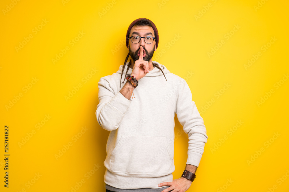 Hippie man with dreadlocks showing a sign of silence gesture putting finger in mouth Hippie man with dreadlocks showing a sign of silence gesture putting finger in mouth