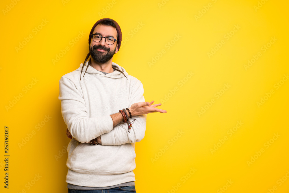 Hippie man with dreadlocks presenting an idea while looking smiling towards Hippie man with dreadlocks presenting an idea while looking smiling towards
