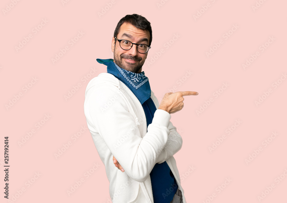 Handsome man with glasses pointing finger to the side in lateral position on isolated pink background Handsome man with glasses pointing finger to the side in lateral position on isolated pink background