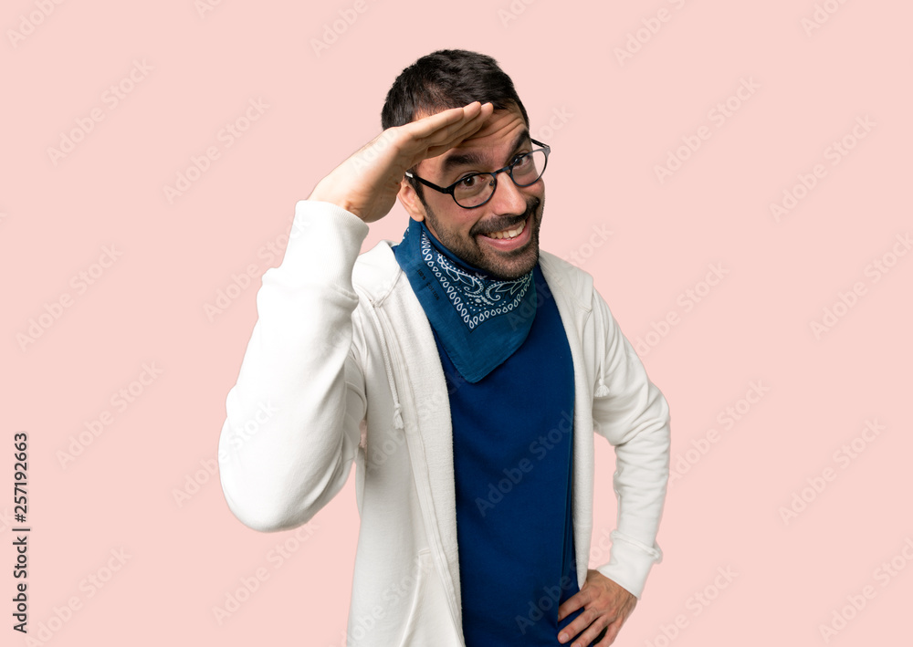 Handsome man with glasses saluting with hand on isolated pink background Handsome man with glasses saluting with hand on isolated pink background