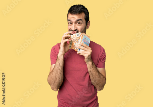 Man taking a lot of money showing a sign of silence gesture on isolated yellow background