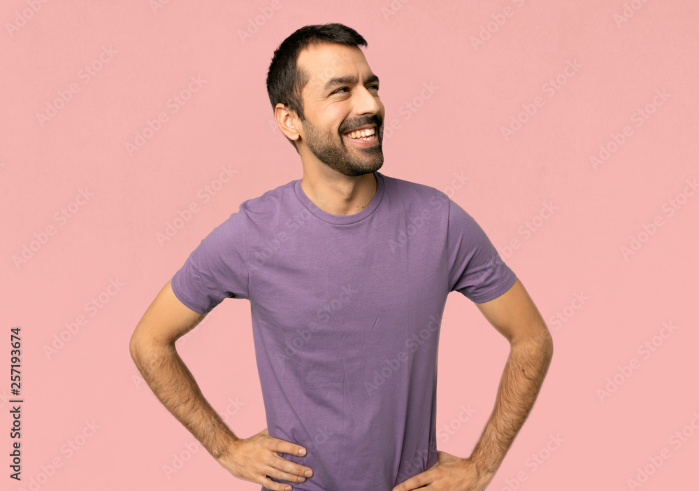 Handsome man posing with arms at hip and laughing on isolated pink background Handsome man posing with arms at hip and laughing on isolated pink background
