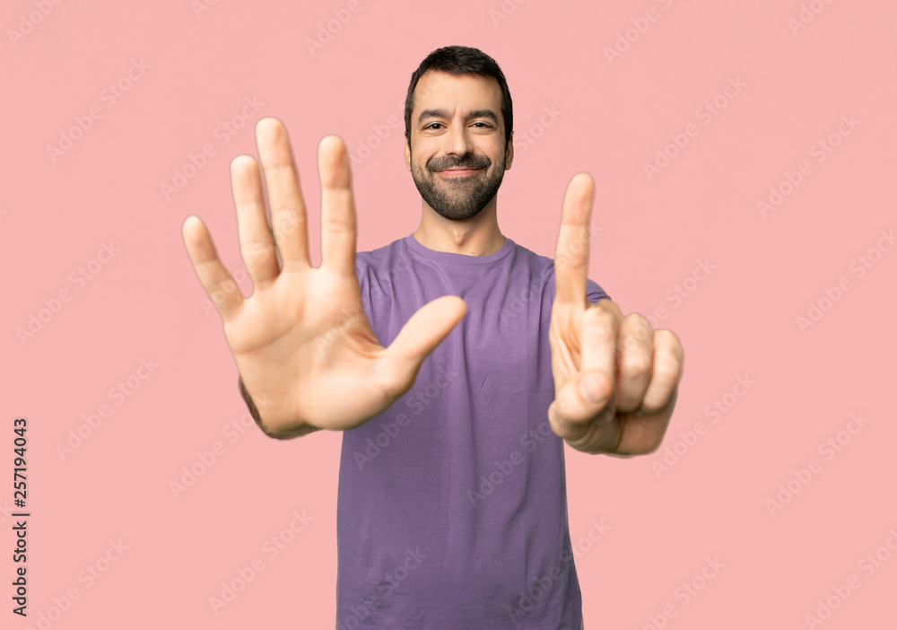 Handsome man counting six with fingers on isolated pink background Handsome man counting six with fingers on isolated pink background