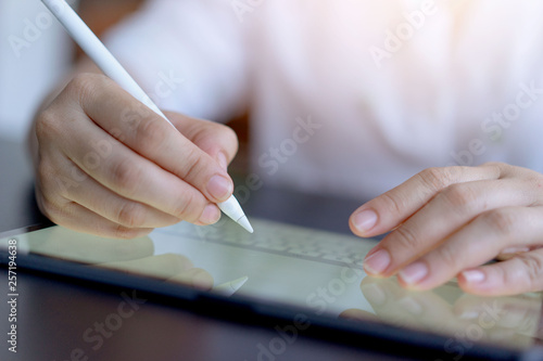 Closeup view of women holding digital tablet on hand using electronic pen while working at office.Pointing tablet screen.Young web designer using digital graphic tablet and drawing pen for new project