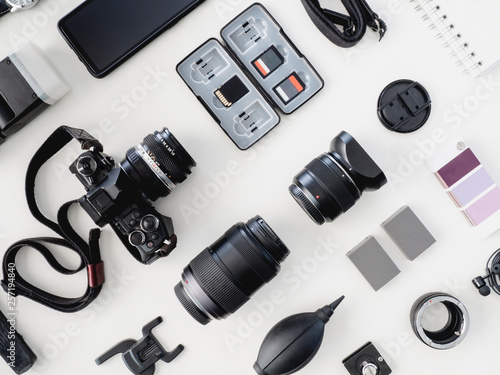 top view of work space photographer with digital camera, flash, cleaning kit and memory card on white table background. photo