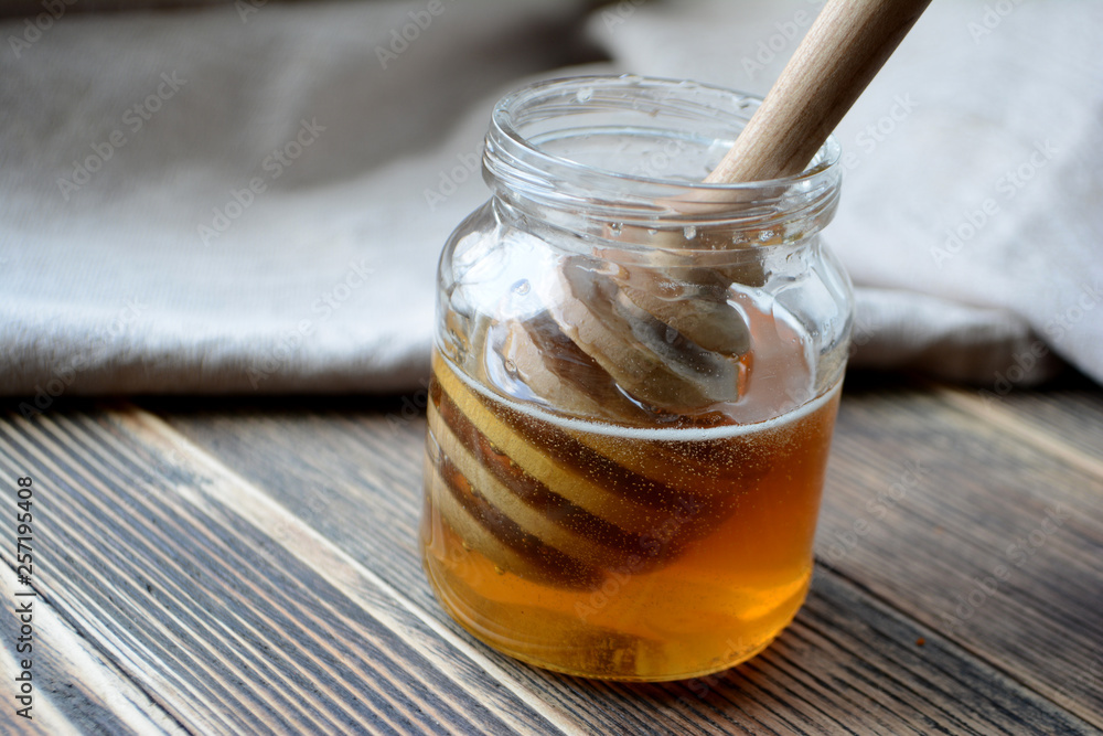 Honey in a transparent jar with a honey spoon Honey in a transparent jar with a honey spoon