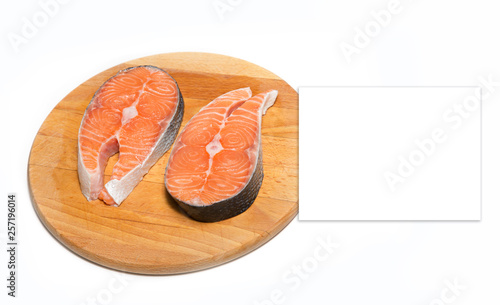 Two steaks of fresh salmon fish meat before cooking lie on a wooden board isolated on a white background. Place for price.