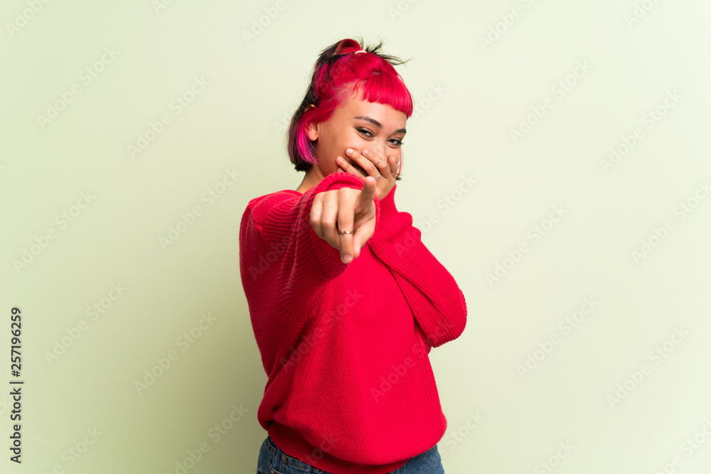 Young woman with red sweater pointing with finger at someone and laughing Young woman with red sweater pointing with finger at someone and laughing