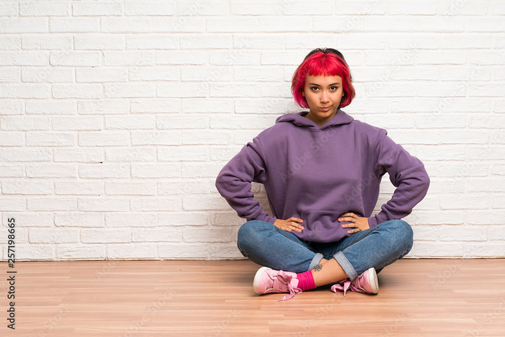 Young woman with pink hair sitting on the floor angry Young woman with pink hair sitting on the floor angry