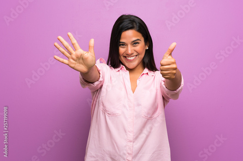 Young Colombian girl over purple wall counting six with fingers