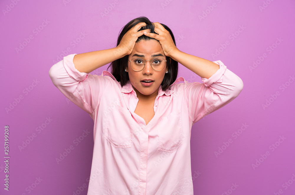 Young Colombian girl over purple wall with surprise facial expression Young Colombian girl over purple wall with surprise facial expression