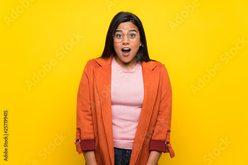 Young Colombian girl over yellow wall with surprise and shocked facial expression © luismolinero