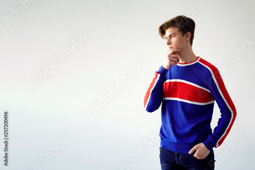 Young cheerful male model wearing bright modern shirt posing on gray background. Copyspace