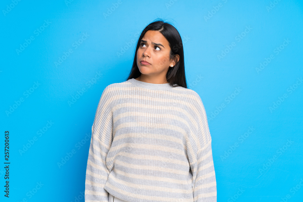 Young Colombian girl with sweater looking up with serious face Young Colombian girl with sweater looking up with serious face