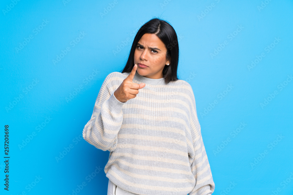 Young Colombian girl with sweater serious and pointing to the front Young Colombian girl with sweater serious and pointing to the front
