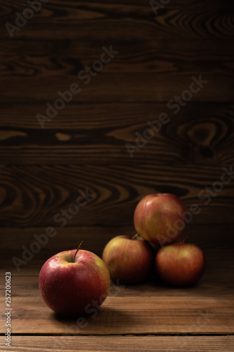 Vertical. Fresh, tasty red apples on a brown wooden table and background. Autumn harvest