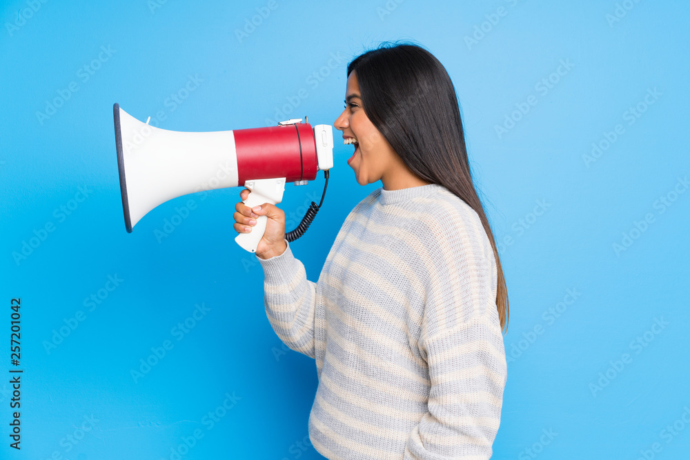 Young Colombian girl with sweater shouting through a megaphone Young Colombian girl with sweater shouting through a megaphone