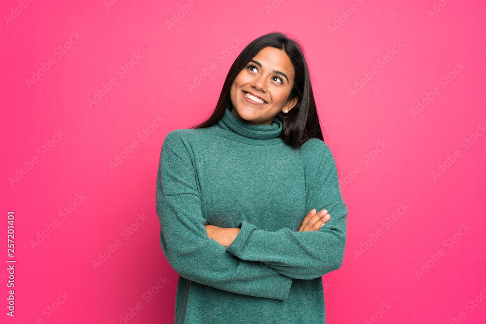 Young Colombian girl with green sweater looking up while smiling Young Colombian girl with green sweater looking up while smiling