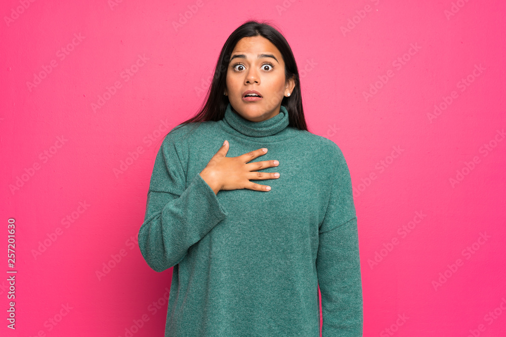 Young Colombian girl with green sweater surprised and shocked while looking right Young Colombian girl with green sweater surprised and shocked while looking right