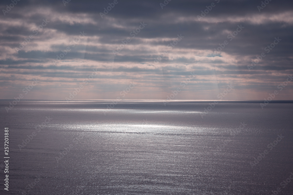 Sunlight through the clouds over the sea, sunbeams, which makes light spot on the surface. Sunlight through the clouds over the sea, sunbeams, which makes light spot on the surface.