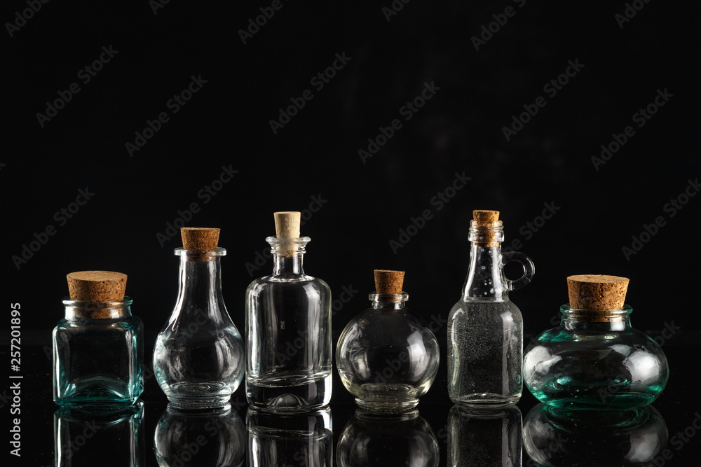 Glass bottles of different shapes and sizes on a black background. Glass bottles of different shapes and sizes on a black background.