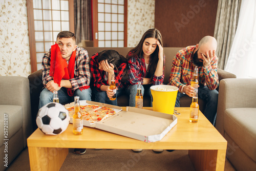 Football fans sadly wathing tv broadcast at home photo