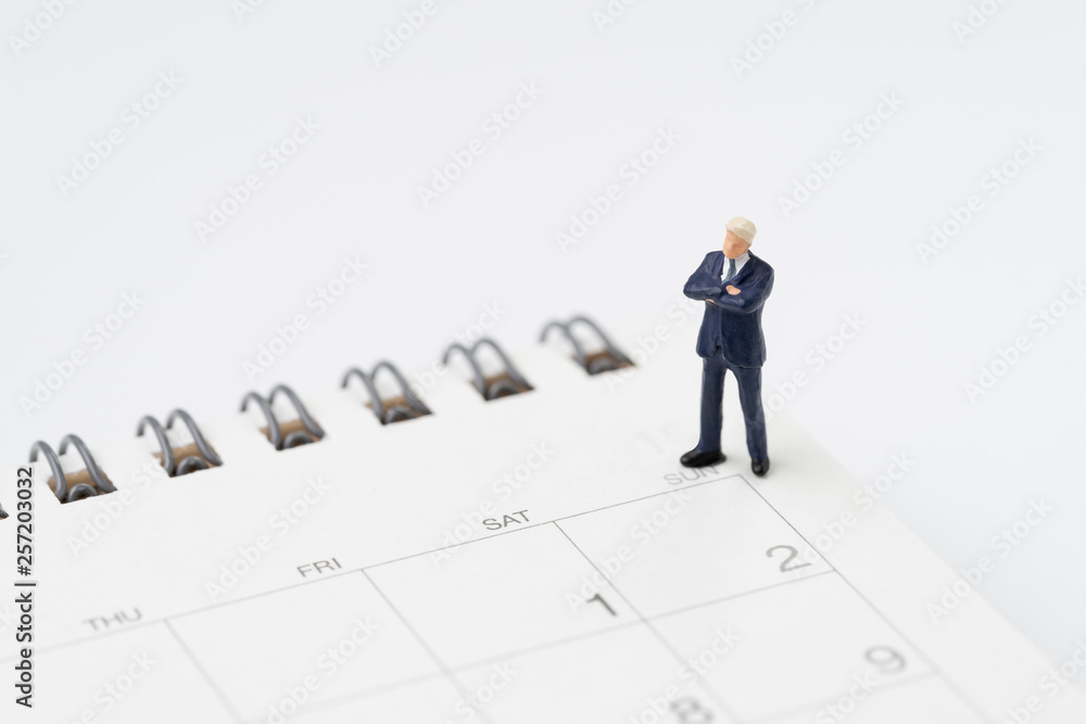 Reminder, schedule or deadline for project launch, confidence miniature businessman standing on the launch date white clean calendar on white background with copy space