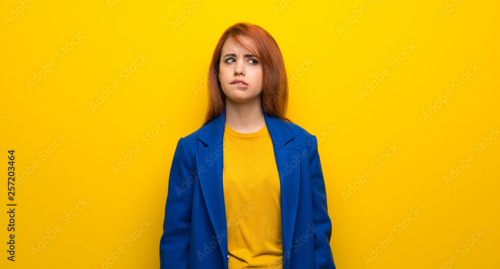 Young redhead woman with trench coat with confuse face expression while bites lip Young redhead woman with trench coat with confuse face expression while bites lip