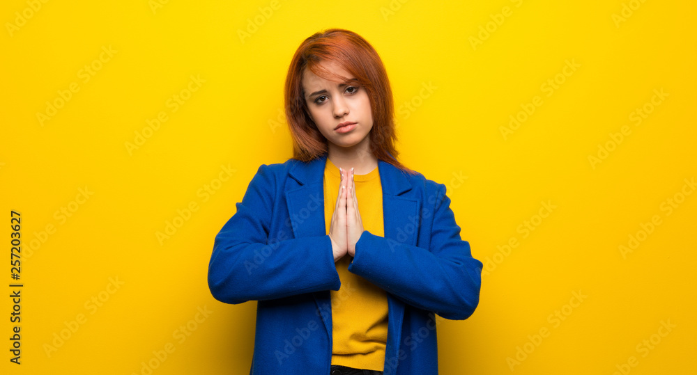 Young redhead woman with trench coat keeps palm together. Person asks for something Young redhead woman with trench coat keeps palm together. Person asks for something