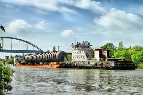 Fotografia Heavy oversized chemical apparatus is transported by river transport through the