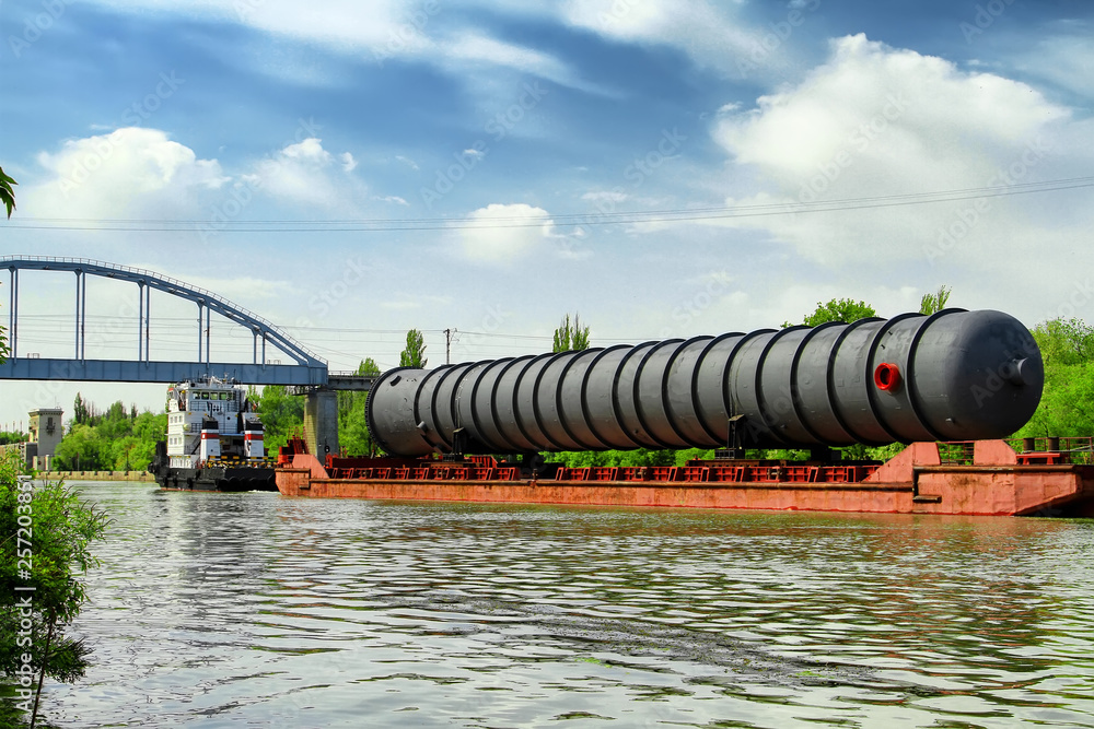 Heavy oversized chemical apparatus is transported by river transport through the shipping channel on a special barge