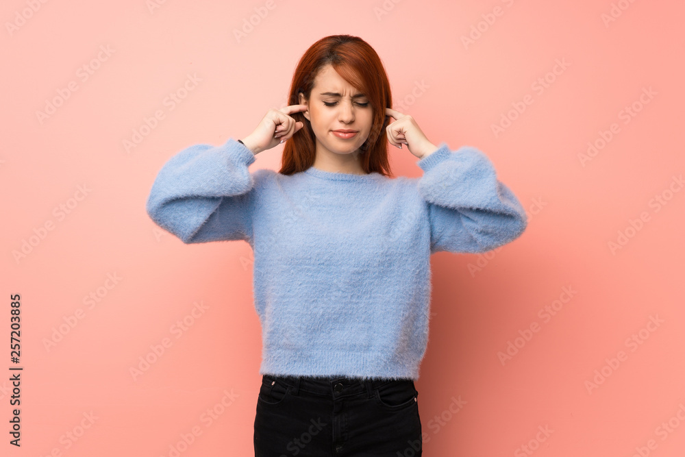 Young redhead woman over pink background covering ears with hands. Frustrated expression Young redhead woman over pink background covering ears with hands. Frustrated expression