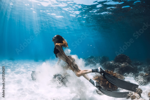 Photography Woman freediver with fins swim over sandy bottom and sun rays underwater ocean