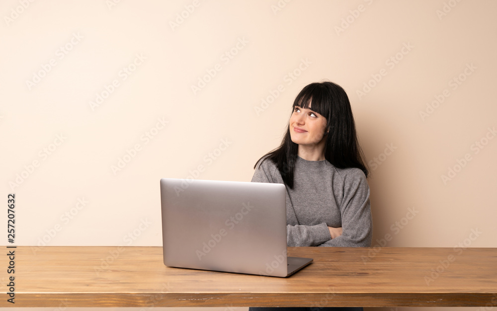 Young woman working with her laptop looking up while smiling Young woman working with her laptop looking up while smiling
