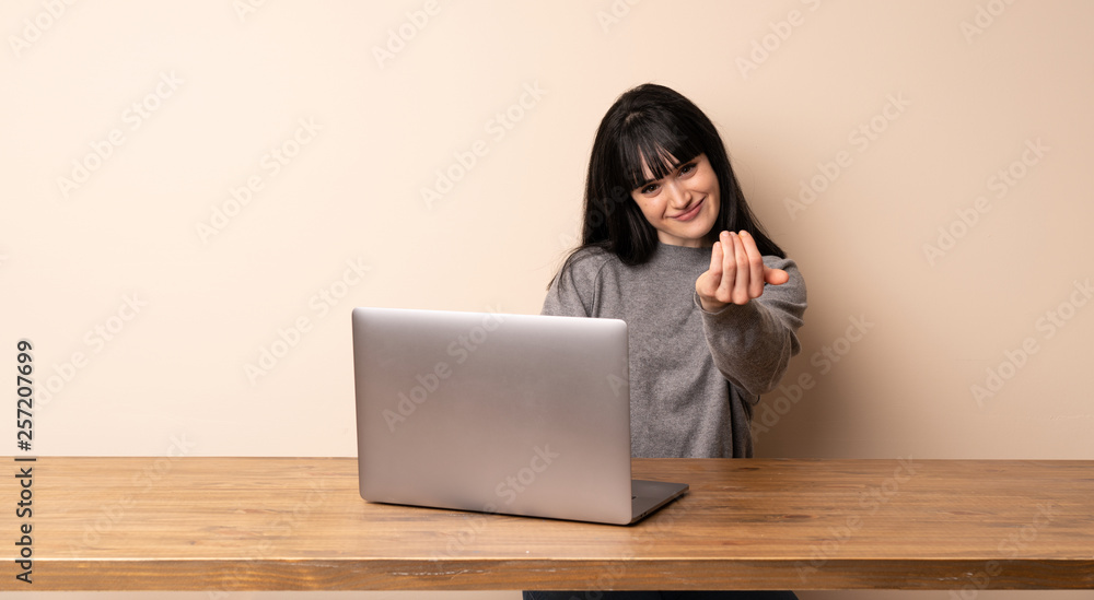 Young woman working with her laptop inviting to come with hand. Happy that you came Young woman working with her laptop inviting to come with hand. Happy that you came
