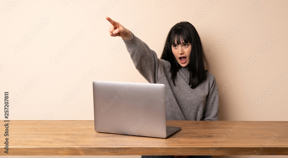 Young woman working with her laptop pointing away Young woman working with her laptop pointing away