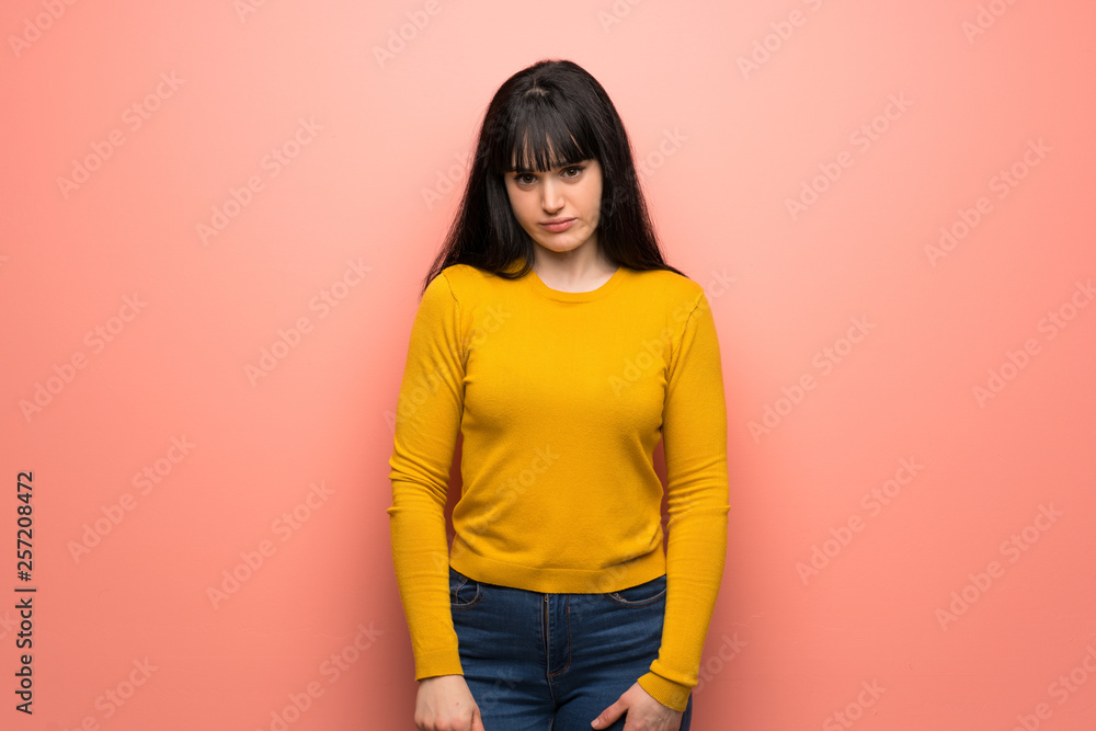 Woman with yellow sweater over pink wall with sad and depressed expression Woman with yellow sweater over pink wall with sad and depressed expression